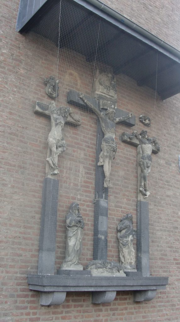 Sixteenth-century group of statues of the Crucifixion, affixed to modern brick wall