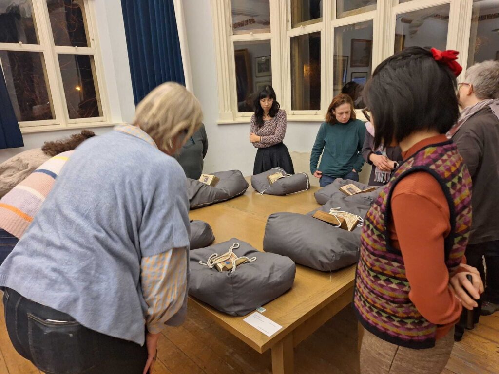 Attendees gather around a table of Books of Hours on cushions.